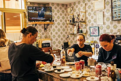 Personal de la cafetería El Pinen, en la barra; de fondo, el presidente Mazón, en la televisión. 