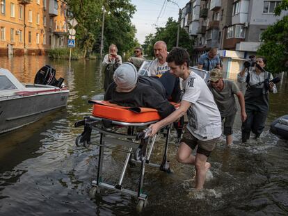 Volunteers haul a woman on a stretcher as she been evacuated from a flooded neighborhood of the left bank Dnipro river, in Kherson, Ukraine, Friday, June 9, 2023.