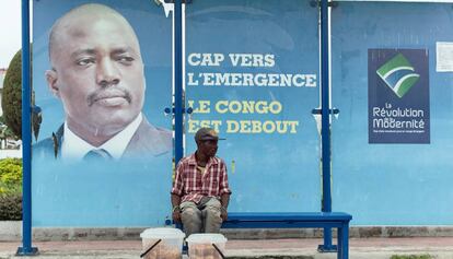 Un vendedor, sentado en una parada de autob&uacute;s con una imagen del presidente Joseph Kabila en Kinshasha, RD Congo. 