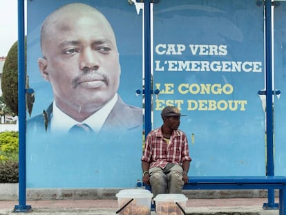 Un vendedor, sentado en una parada de autob&uacute;s con una imagen del presidente Joseph Kabila en Kinshasha, RD Congo. 