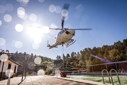 Un helicóptero recoge agua de una piscina para continuar con los trabajos de refresco del incendio en  Villanueva de Viver, este miércoles.