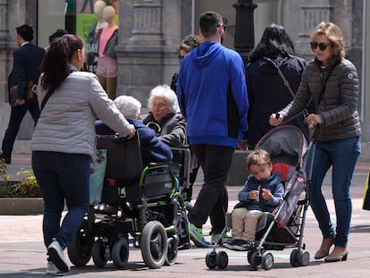 Una mujer empuja un carrito de bebé, mientras otras dos llevan a personas mayores en sillas de ruedas, en una imagen de 2019 en Oviedo.