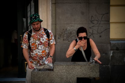 Dos turistas beben agua en una fuente en el centro de Madrid, este viernes.
