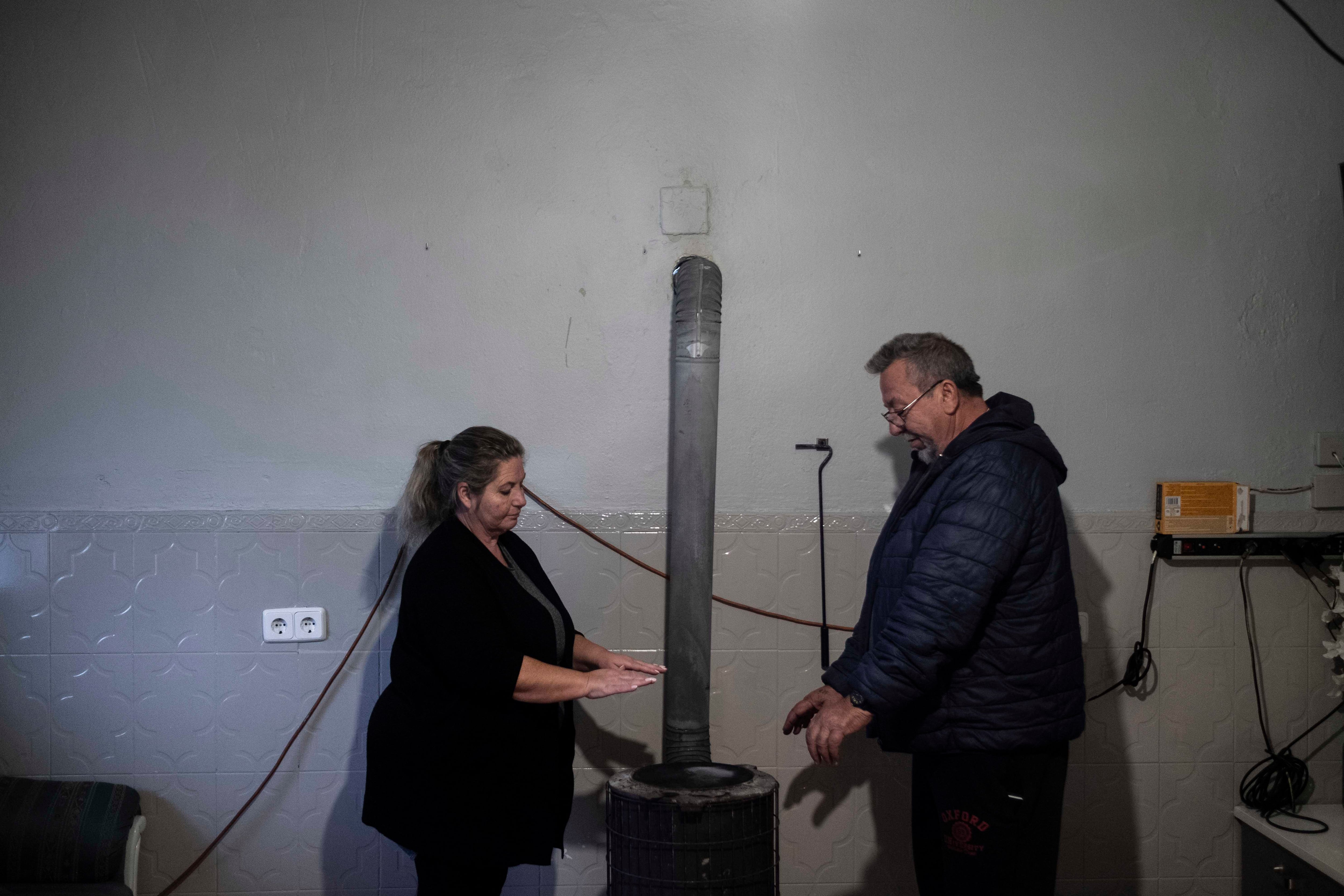 María y Pedro, vecinos del sector seis de la Cañada Real desde hace más de 30 años, se calientan en una estufa que se han visto obligados a instalar por el corte de luz.