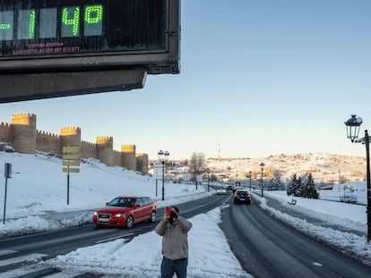Un hombre toma una fotografía con su móvil de un termómetro que marca 14 grados bajo cero, este martes junto a la muralla de Ávila.