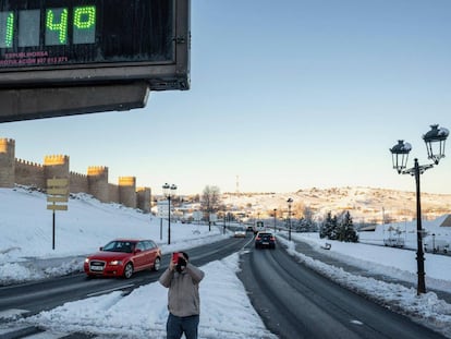 Un hombre toma una fotografía con su móvil de un termómetro que marca 14 grados bajo cero, este martes junto a la muralla de Ávila.