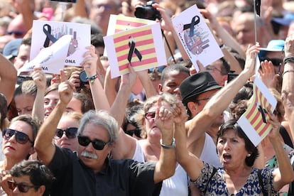 Un grupo de gente sostiene carteles en apoyo a las víctimas del atentado durante el minuto de silencio en la Plaza de Cataluña de Barcelona.