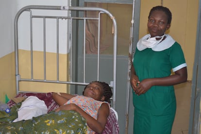 Cynthia, una mujer que acaba de dar a luz, descansa en una cama del hospital de Ankaful, en Ghana. Esther Appoh, matrona del mismo centro, permanece a su lado.