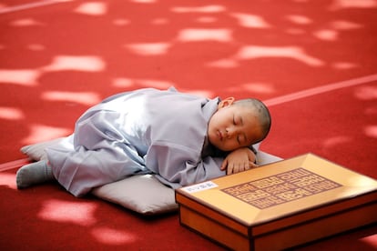 Un joven monje duerme la siesta después de que le afeitaran la cabeza con motivo de las celebraciones del Día de Vesak, cumpleaños de Buda, en el tempo Jogye en Seúl (Corea del Sur).