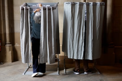 Dos personas en el interior de una cabina eligen su voto este domingo en plaza Universidad de Barcelona.