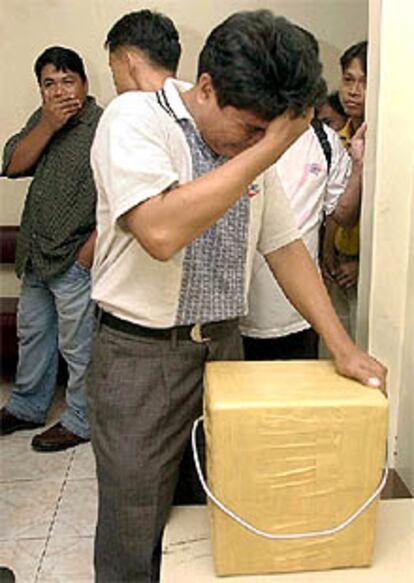 Un hombre llora ante una caja con la cabeza de su hermano.