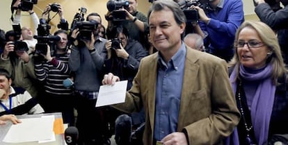 El candidato de CIU a la presidencia de la Generalitat, Artur Mas, acompañado de su esposa Helena, momentos antes de introducir su voto en el colegio electoral Infant Jesús de Barcelona.