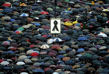 Un gran lazo negro domina sobre los paraguas en la plaza de Colón en la manifestación contra los atentados del 11-M, el 12 de marzo de 2004 en Madrid.