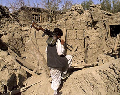 Un combatiente de la Alianza del Norte camina sobre las ruinas de una casa destruida por los bombardeos estadounidenses en Ghanee Jil.