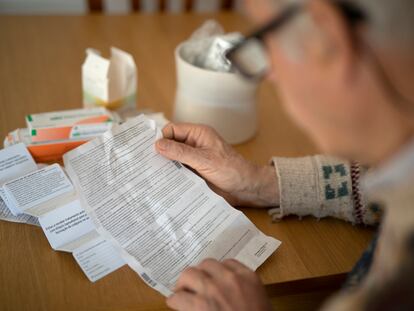 Un usuario lee el prospecto de uno de los medicamentos que debe tomar en el salón de su casa.