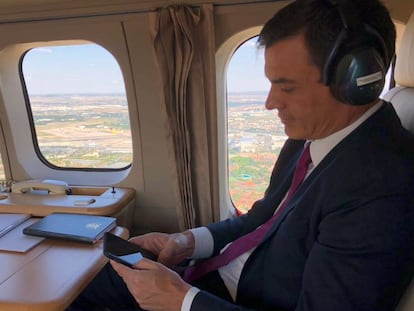 El presidente del Gobierno, Pedro Sánchez, mira su 'smartphone' en un viaje oficial.
