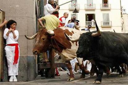 Una moza se protege en el tramo de Mercaderes al paso de los toros de Osborne.