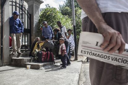 Un hombre sostiene el periódico semanal La Razón con el titular ‘Estómagos vacíos’ mientras un grupo de personas esperan al reparto sabatino de comida en La Olla Solidaria. La joven Alesia Santacroce es la impulsora de la Olla Milagrosa, una iniciativa que surgió “para poder ayudar a quienes ya no hablan de crisis, sino de ausencia; quienes no conocen la dificultad sino la necesidad; quienes no tienen qué comer y no han conseguido nada en todo el día”.