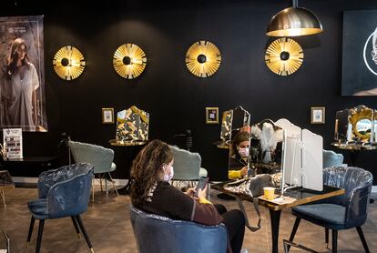 Una mujer espera a que se seque el barro con el que le han tratado el cabello en una peluquería en Valdebebas.