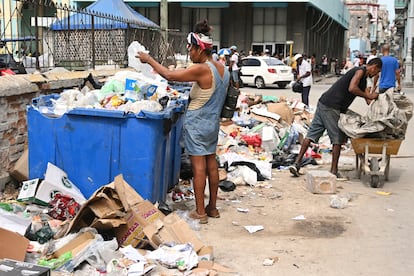 Unos cubanos buscan insumos en la basura.