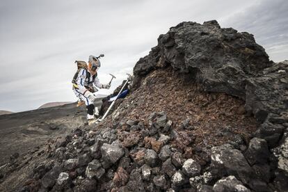 Un astronauta recoge muestras superficiales de un campo de lava.