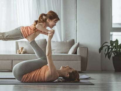 Una madre y su hija hacen ejercicio en su casa. 