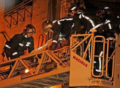 Los bomberos bajan en la grúa a la mujer de 98 años que sobrevivió a la explosión de su vivienda, en Alcalá de Henares.