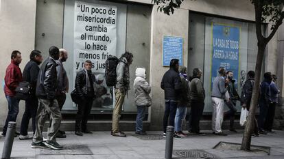 Ciudadanos con problemas económicos esperan para recoger el almuerzo ofrecido en el comedor social de la iglesia de San Antón, en Madrid.