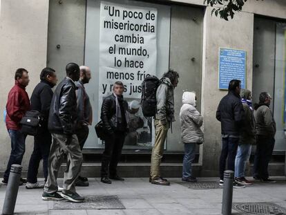 Ciudadanos con problemas económicos esperan para recoger el almuerzo ofrecido en el comedor social de la iglesia de San Antón, en Madrid.