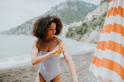 Una mujer aplica protección solar en una playa.