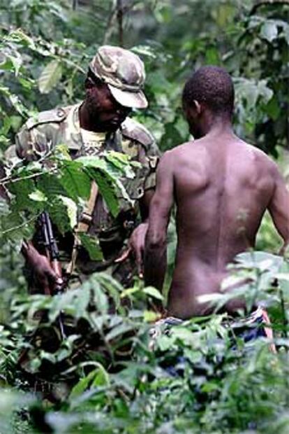 Un soldado guineano escruta el cuerpo de un refugiado liberiano.