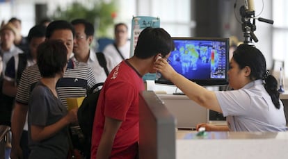 Un trabajador del Aeropuerto Internacional de Incheon (Corea del Sur) controla la temperatura corporal de un pasajero para descartar la posible infección del virus del Ébola antes de embarcar hacia su destino.