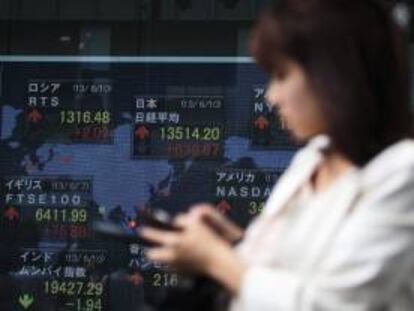Una mujer camina junto a una pantalla que muestra información bursátil en Tokio (Japón). El índice Nikkei de la Bolsa de Tokio abrió hoy con una subida de un 2,61 por ciento. EFE/Archivo