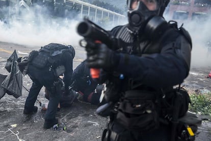 El pasado martes un oficial de la policía antidisturbios apunta con su lanzador de proyectiles mientras sus colegas detienen a los manifestantes en el distrito de Sha Tin de Hong Kong.