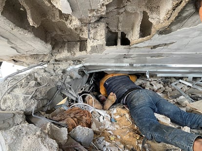 Un hombre trata de sacar el cuerpo de un familiar de debajo de los escombros ocasionados por un bombardeo israelí en el campo de refugiados de Al Maghazi, en el centro de Gaza, este lunes.