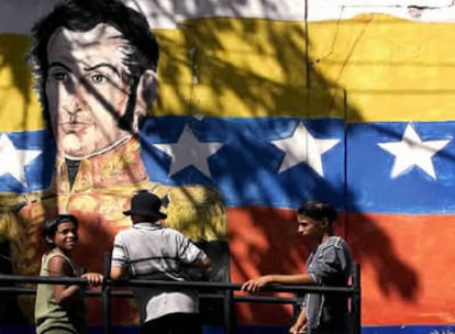 Niños frente a una pintada en la pared en la que aparece, la bandera de Venezuela y un retrato de Simón Bolivar.