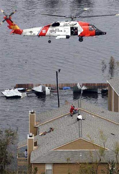 Un helicóptero inicia el rescate de varias personas situadas en el tejado de una vivienda.