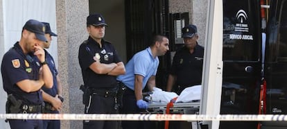 Los servicios funerarios trasladan una víctima desde la escena del crimen.