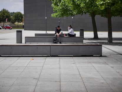 Dos jóvenes hablan en un banco junto a Baluarte, Palacio de Congresos y Auditorio de Navarra.