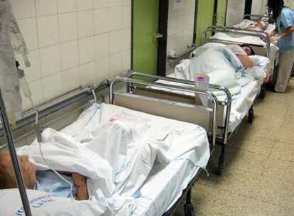 Varios pacientes esperan en los pasillos de Urgencias de La Paz a que les lleven a una habitación. Al fondo, una enfermera les atiende.