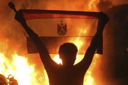 Un manifestante sostiene la bandera egipcia al lado de las llamas de un incendio junto a la Embajada de Israel en El Cairo.