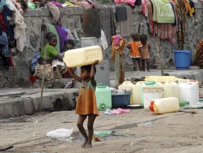 Una niña carga con un bidón para el agua en Bombai (India)
