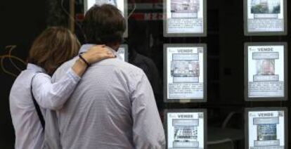 Una pareja mira ofertas de viviendas en una inmobiliaria de Madrid