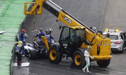 Lewis Hamilton se aleja de su coche recién estrellado, mientras lo retira una grúa.