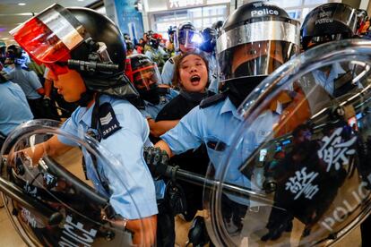 La policía antidisturbios detiene a una mujer mientras los manifestantes se reúnen en la estación de ferrocarril de tránsito masivo Sha Tin (MTR) para manifestarse contra el operador del ferrocarril, al que acusan de ayudar al gobierno, en Hong Kong.