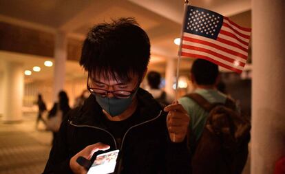 Un manifestante prodemocracia sostiene una bandera de Estados Unidos mientras revisa su teléfono, este jueves en Hong Kong.