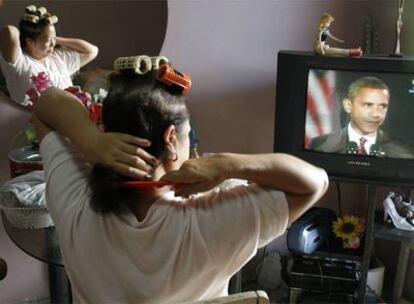 Una mujer se peina ayer en La Habana mientras sigue en la televisión cubana las informaciones sobre las elecciones en Estados Unidos.