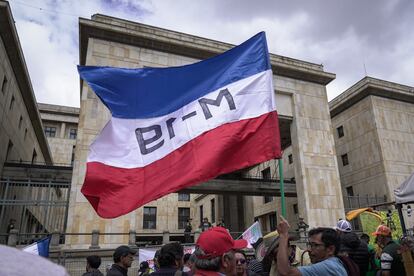 Un manifestante ondea la bandera del M-19 frente al Palacio de Justicia.