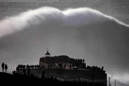 Turistas observan una ola gigante junto al fuerte de São Miguel Arcángel, en Praia do Norte, en Nazaré (Portugal).
