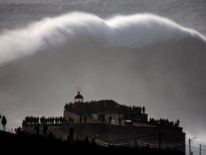 Turistas observan una ola gigante junto al fuerte de São Miguel Arcángel, en Praia do Norte, en Nazaré (Portugal).